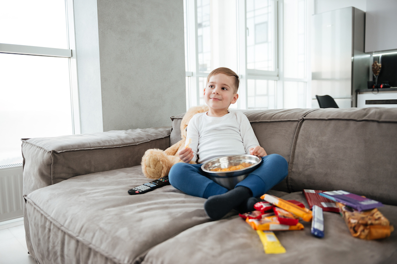 enfants qui regarde la télé en mangeant des produits sucrés